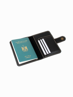 Black leather passport holder with a green passport inside on a white background