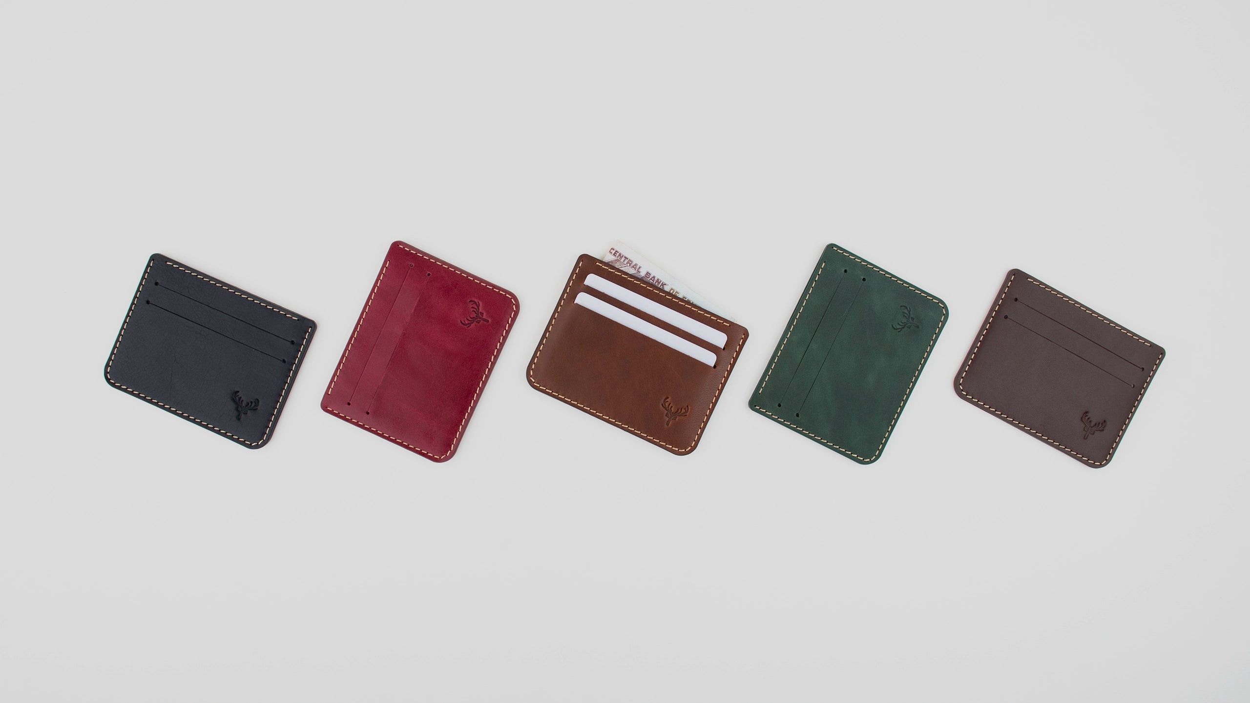 Five different colored wallets arranged in a row on a light gray background